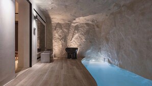 A spa with a stone wall, a bathtub, and a wooden floor.
