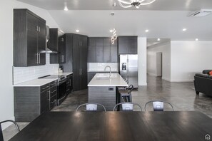 Une cuisine moderne avec des meubles de couleur sombre, un îlot central et un coin repas comprenant une table et des chaises en bois foncé.