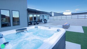 A modern outdoor hot tub area with a seating area and a fire feature. - Desert Dreams Moab with Home EV Charging (Moab)
