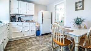 A compact kitchen with white cabinets, a refrigerator, a coffee maker, and a dining table with chairs. - Jacuzzi room - 2 Queen beds (OGUNQUIT)