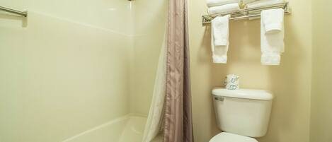 A bathroom with a bathtub, toilet, and shower curtain.