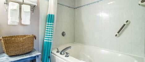A bathroom with a bathtub, a shower, and a towel rack with folded towels.