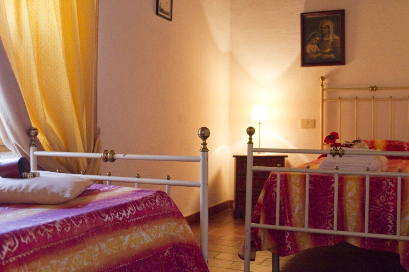 A room with two beds, a nightstand, a lamp, and a painting on the wall.