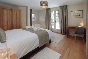 Une chambre à coucher avec un grand lit, un bureau, une chaise et une fenêtre avec des rideaux.