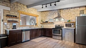 Una cocina con armarios de madera oscura, lavavajillas de acero inoxidable, horno empotrado, microondas y refrigerador.