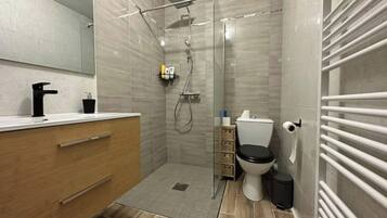Een moderne badkamer met een douche, toilet en wastafel.