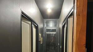 Un couloir étroit avec un plancher en bois et des murs sombres.