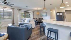 A modern kitchen with a bar area, a dining table, and a seating area with a sofa and chairs. - 92 Forest Gardens: Newly Remodeled Villa, Walk to Beach, Pool, Free Bikes (Hilton Head Island)