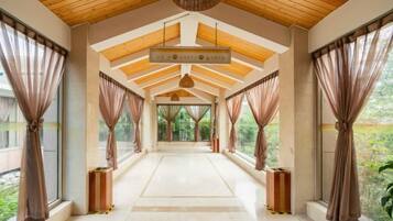 A corridor with a high ceiling, large windows, and curtains.