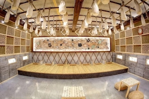 Une pièce spacieuse dotée d’un espace salon central, de murs à motifs, de luminaires suspendus et d’un grand ensemble d’œuvres d’art exposées.