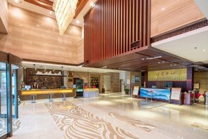 A spacious lobby with a reception desk, seating area, and a large digital display. - Shanghe Hotspring Hotel (Shanghe)