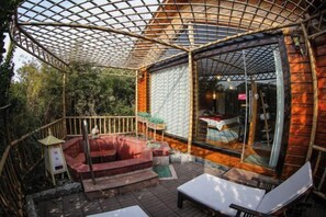 A wooden cabin with a glass door, a covered outdoor seating area, and a wooden deck. - Shanghe Hotspring Hotel (Shanghe)