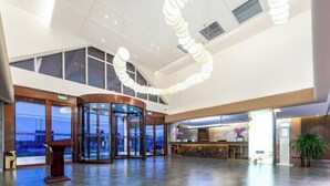 Un'ampia hall con una porta girevole, una reception e un'abbondante pianta in vaso.