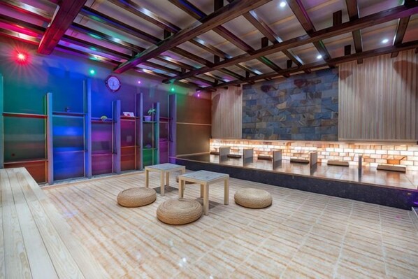 A spa area with wooden flooring, seating, a stone wall, and a reception desk.