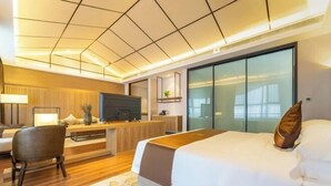 Una camera d'albergo moderna con un letto grande, una scrivania, una sedia, una televisione e un'ampia finestra.