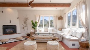 A cozy living room with a fireplace, a sofa set, a coffee table, and a view of the outdoors.