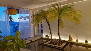 A room with a large window, a palm tree, and a small water feature. - Suite with pool and mountain view / Suite with pool and mountain view (San Andrés Huayápam)