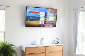 A flat-screen TV mounted on a wall displaying a streaming service interface with various channels.