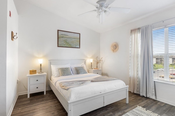 Bright and airy bedroom with cozy bedding, blackout curtains, and plenty of natural light—perfect for a restful night’s sleep.