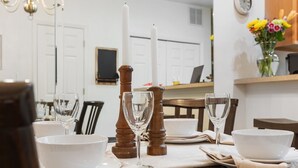 Una mesa de comedor dispuesta con cuencos blancos, copas de vino y salero y pimentero.