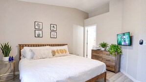 A bedroom with a bed, bedside tables, a dresser, wall art, and a TV.