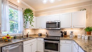 A kitchen with white cabinets, a stainless steel dishwasher, a microwave, an oven, and a granite countertop.