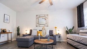 A modern living room with a sectional sofa, a round coffee table, and a bed.