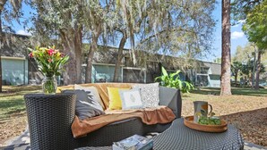 An outdoor seating area with wicker furniture, a book, and a drink tray. - The YinYang | King Bed • Workspace • Full Kitchen (Gainesville)