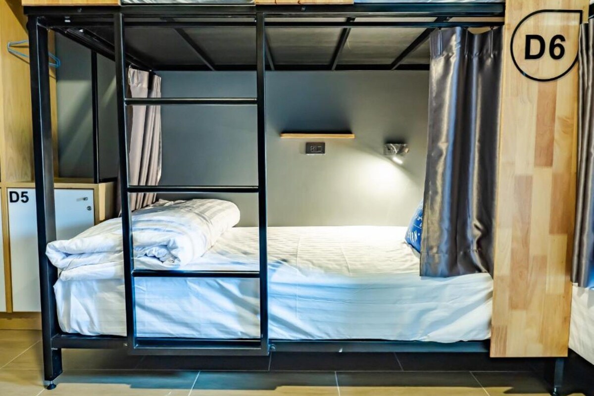 Un lit superposé avec une tête de lit en bois et une petite étagère au-dessus.