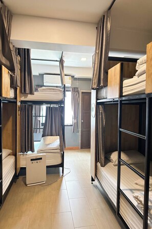 A dormitory room with bunk beds, a heater, and a window with curtains. - Ray Hostel by Zuzu (Chiang Mai)