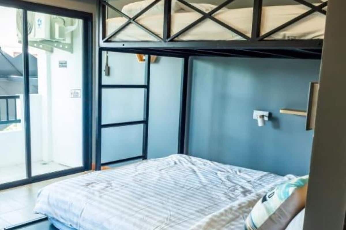 A modern bedroom with a bunk bed, a large window, and a sliding door to a balcony.