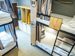 A dormitory room with bunk beds, a wooden wardrobe, and a small desk area. - Ray Hostel by Zuzu (Chiang Mai)