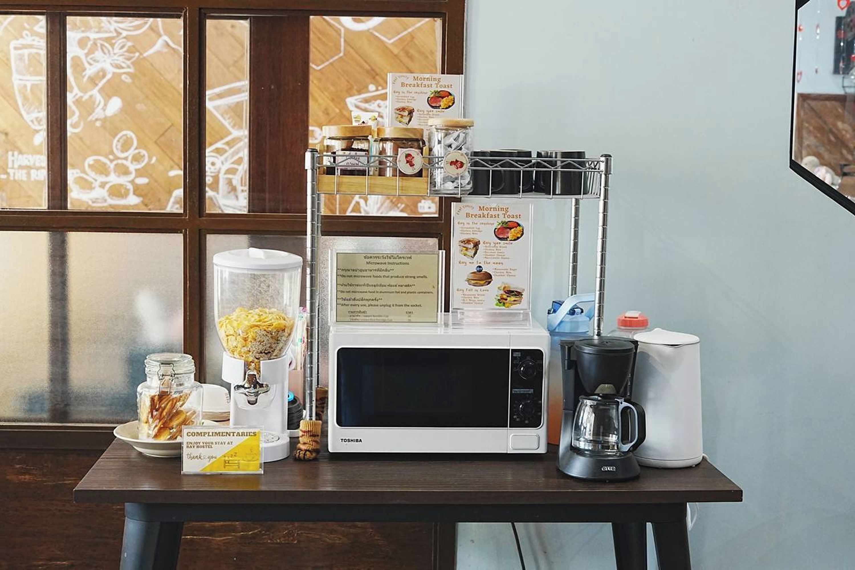 A breakfast setup with a microwave, coffee maker, and a menu on a table.