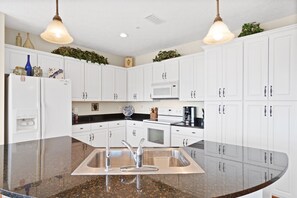 Fully equipped kitchen with a stainless steel sink, microwave, coffee maker, and refrigerator.