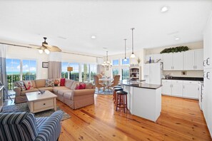 Relax in a spacious living area with a modern kitchen and dining space, featuring a sofa set, coffee table, and armchair.