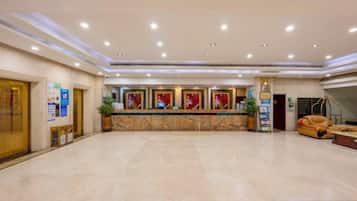 A spacious lobby with a reception desk, seating area, and a large window.