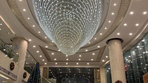 Un vaste atrium doté d’un grand lustre circulaire et d’un escalier central.