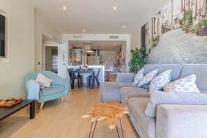 Una sala de estar con sofá, mesa de centro y comedor con sillas y mesa.