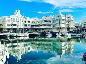 A marina with multiple boats docked, surrounded by white buildings with balconies. - Luxury Waterfront Apartment with Pool, Terrace and Wi-Fi (Benalmádena Costa)