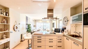 Una cocina moderna con una isla central, electrodomésticos integrados y un ventanal grande.