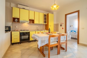 Une cuisine avec des meubles de rangement jaunes, une table à manger avec des chaises, une cuisinière et un four à micro-ondes.