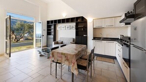 Cozinha moderna com área de refeições, prateleiras embutidas e vista através de uma porta de vidro.