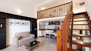 Um apartamento moderno com área de estar, cozinha e escada de madeira.