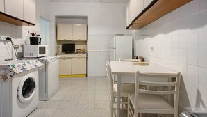 A compact kitchen with a washing machine, microwave, and refrigerator.