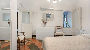 A bedroom with a bed, a dresser, a chair, a vanity, and a window with a view.