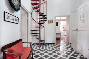 A hallway with a spiral staircase, a red sofa, and a checkered floor.