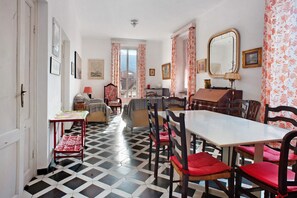 Un'area pranzo con pavimento a scacchi, un tavolo da pranzo con sedie e vista attraverso una porta.