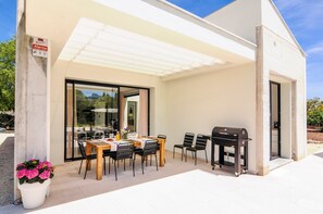 An outdoor patio with a dining table, chairs, a grill, and a covered area. - Villa 'Hort Petit De Ternelles' with Mountain View, Wi-Fi, Air Conditioning and Underfloor Heating (Mallorca, Illes Balears)