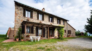 A stone house with a covered porch, a gravel driveway, and a small table and chairs outside. - Apartment "Lavanda" with Mountain View, Shared Pool & Wi-Fi (radicofani)