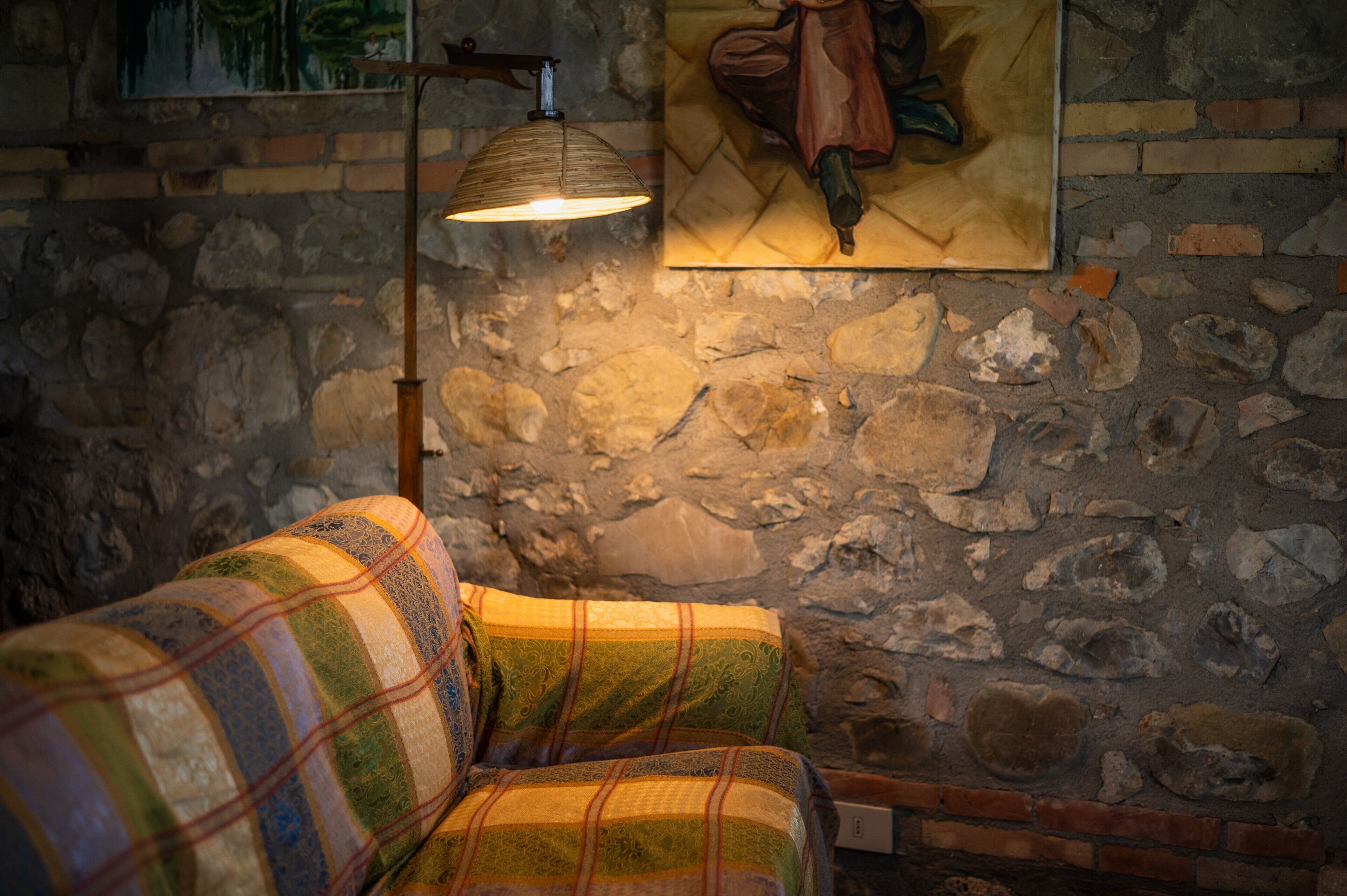 Eine Steinsäule, eine Lampe und ein gemustertes Sofa in einem Raum.